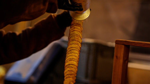 圣诞市集售卖螺旋形炸薯片“卷曲薯片”;露天夜市的龙卷风土豆串;用扭曲或龙卷风照片薯片制作街头小吃;薯片串;街头小吃亭的薯片图片下载