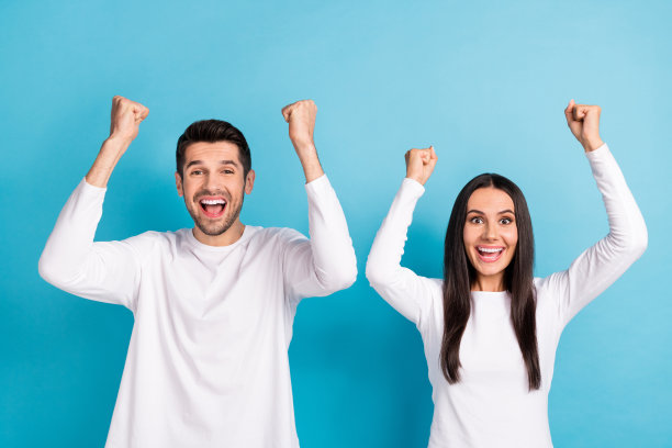 可爱的年轻男人的照片肖像，女人兴奋地举起手臂庆祝成功，穿着时尚的白色衣服，孤立在蓝色的背景下图片下载