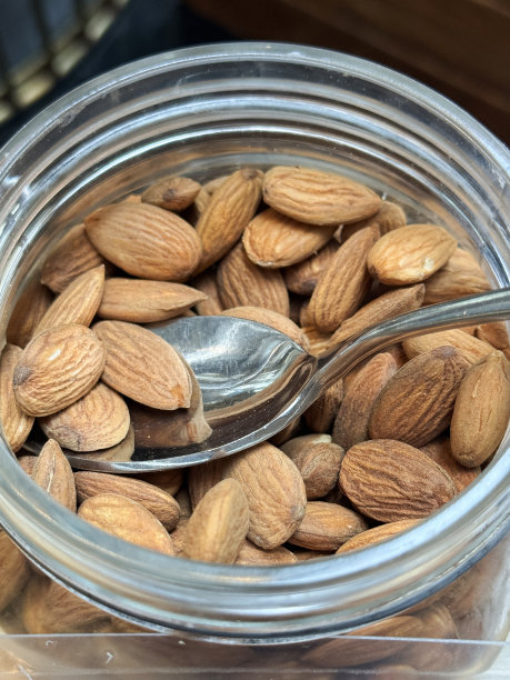 酒店自助早餐的特写图片，展示了开放式的、玻璃的、装有杏仁的储物罐、金属勺子、自制什锦早餐的配料图片下载