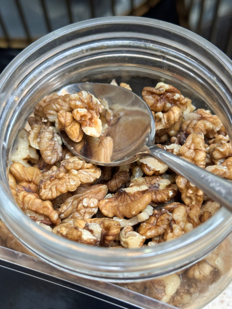 酒店自助早餐的特写图片，展示了开放式的、玻璃的、带有金属杠杆臂夹的储物罐，里面装着去壳的核桃，金属上菜勺，自制什锦早餐的配料，高架视图图片下载