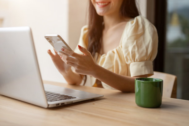 这是一张裁剪过的照片，一位女士在室内的一张桌子上查看信息或刷智能手机。图片下载