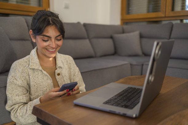 漂亮女孩在公寓里一边看电影一边发短信。图片下载