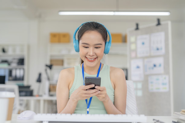 快乐的女人用智能手机，听音乐，播放列表，从耳机休闲布放松清新的时刻，在现代办公室内部休息图片下载