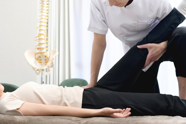 亚洲男性脊医或物理治疗师在按摩床上为女病人做足部按摩图片下载