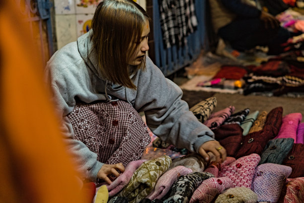 在印度大吉岭购物街的傍晚，一位年轻的亚洲女性在街头售卖温暖的羊毛衣服图片下载