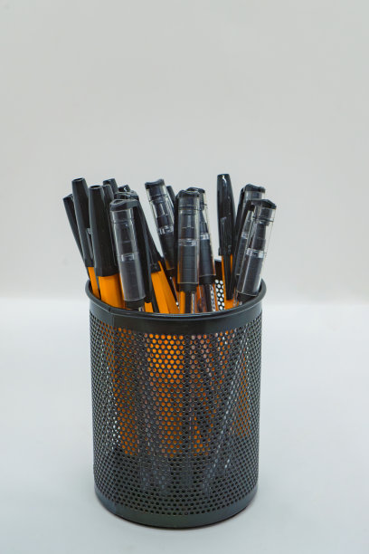 一个笔筒，里面有黑色和橙色的圆珠笔图片下载