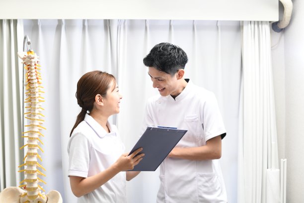 一名身穿白大褂的女医务人员微笑着与一名男医务人员交谈图片下载