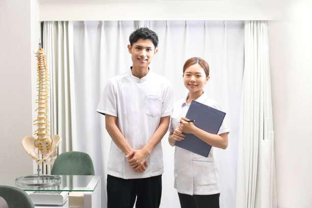 身穿按摩师或理疗师白大褂的男女正微笑着看着镜头图片下载