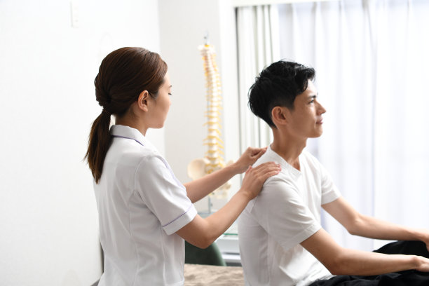 亚洲女脊医或物理治疗师为男病人进行按摩治疗，以检查病人的脊椎状况图片下载