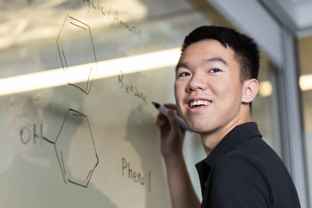 一个年轻人在玻璃白板上画有机化合物图片下载