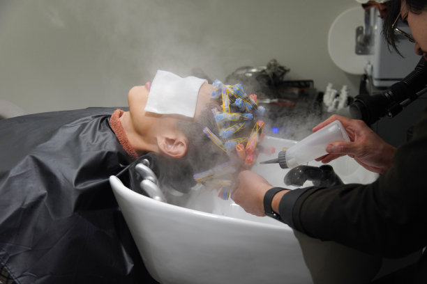 男理发师在头发上涂抹化学物质图片下载