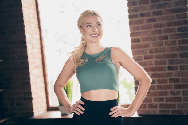 照片积极的女运动员看侧面穿品牌运动服在房子的室内图片下载