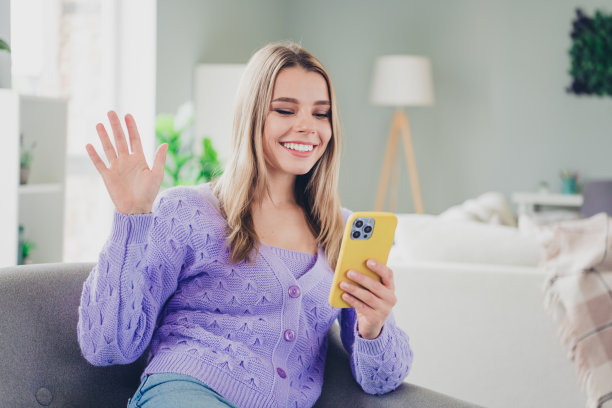 可爱开朗的女孩照片坐在扶手椅小工具视频打电话挥手hi穿着紫色的衣服度过休闲宽敞的房子在室内房间图片下载