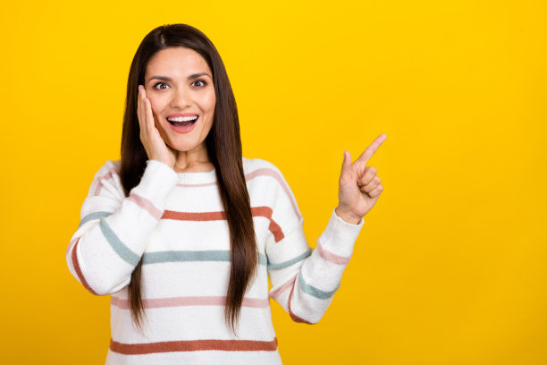 黑色头发的肖像照片迷人的快乐女孩可爱穿着条纹毛衣指着手指惊人的新闻孤立在黄色背景图片下载