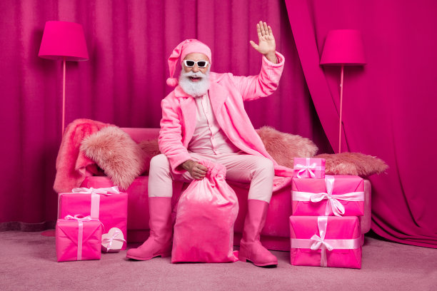 时髦奢华的圣诞老人的照片，坐在沙发沙发上挥手祝贺新年，在房间内部拿着麻袋礼物图片下载