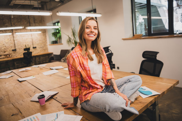 全尺寸照片的年轻企业妇女坐在办公桌阁楼室内商务中心办公室室内图片下载