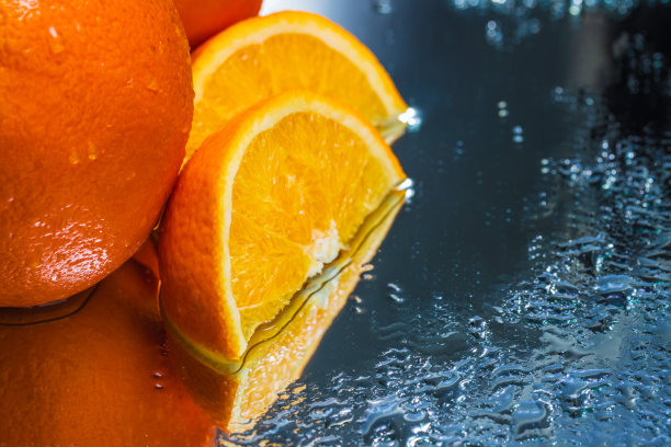 整个和切片橙子在反射表面上的抽象排列-库存照片图片下载