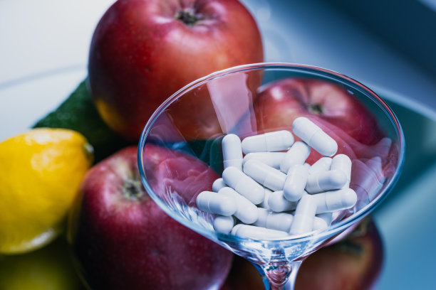 彩色水果与药丸在蓝色背景上的玻璃杯-健康概念-库存照片图片下载