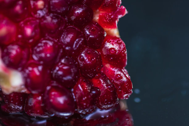 极端特写切片石榴在一个反射表面-库存照片图片下载