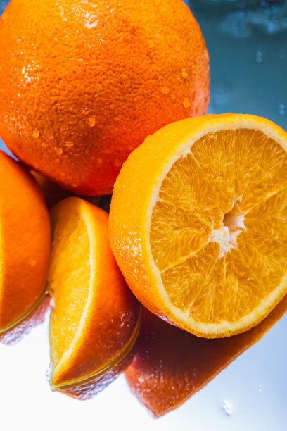 整个和切片橙子在反射表面上的抽象排列-库存照片图片下载