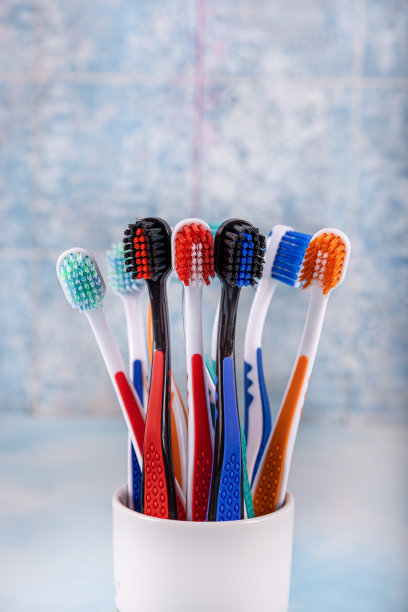 背景模糊的陶瓷碗牙刷。早上卫生。浴室配件图片。蓝色背景的牙刷。彩色牙刷，健康牙齿理念。图片下载
