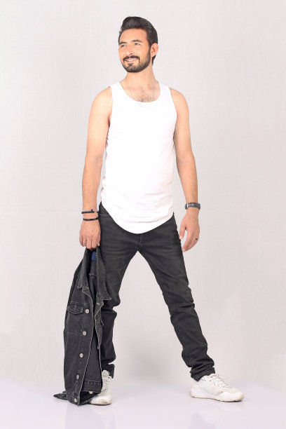 一个年轻的时尚男子的肖像在白色背景与黑色牛仔裤夹克全高和坐着的照片带着微笑图片下载