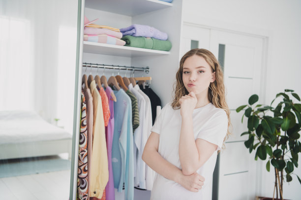 照片甜美漂亮的少女心思选择服装穿睡衣白色室内卧室公寓图片下载