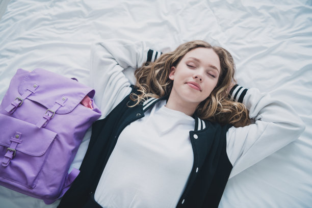 照片甜美漂亮的十几岁的女孩躺在床上睡觉放松穿着时尚的校服早上例行白色室内卧室公寓图片下载