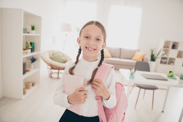 照片中可爱的小学生拿着书包书本穿着校服客厅公寓室内图片下载