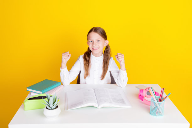 照片肖像可爱的小女生做作业获胜穿着时尚的制服孤立在黄色的背景图片下载