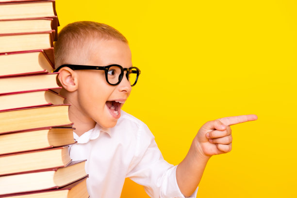 照片中聪明伶俐的男孩穿着白衬衫堆叠书推荐空白空间孤立在黄色背景上图片下载