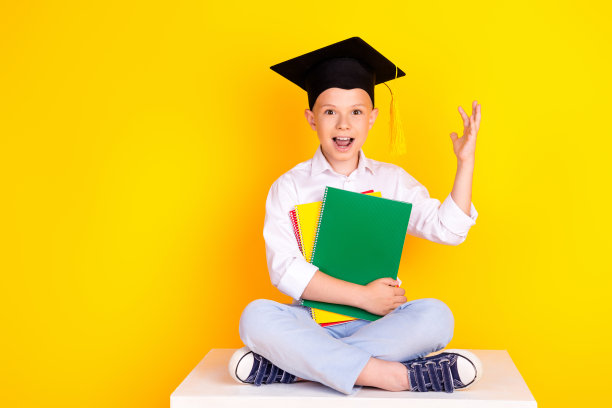 照片开朗迷人的快乐男孩毕业戴着帽子拿着书孤立的黄色背景图片下载