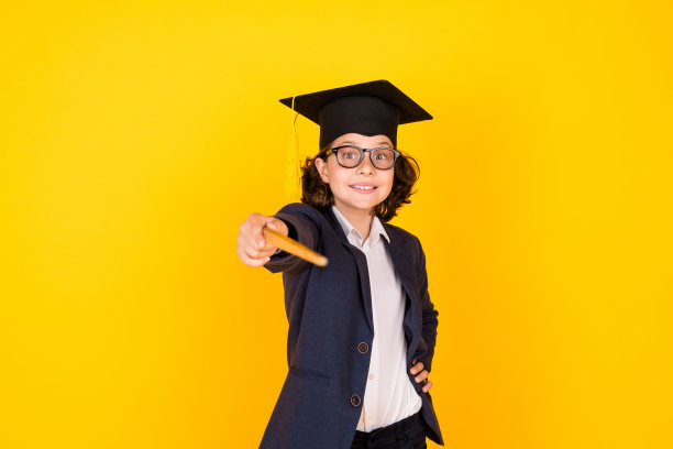 照片肖像的小学生男孩点你贴指针穿时髦的制服孤立在黄色的背景图片下载
