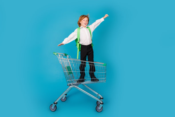 小学生在市场手推车内的全尺寸照片，穿着蓝色背景的制服图片下载