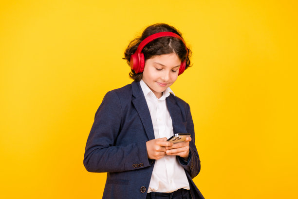 小男孩的照片肖像耳机手持设备穿着时髦的制服孤立的黄色背景图片下载