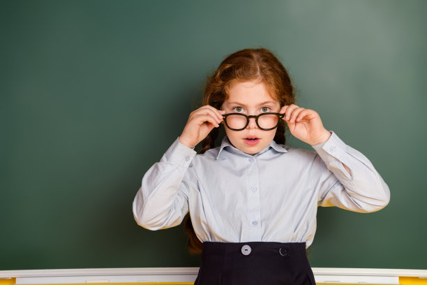 照片中的小女生凝视着空旷的空间，穿着校服孤立在黑板背景上图片下载