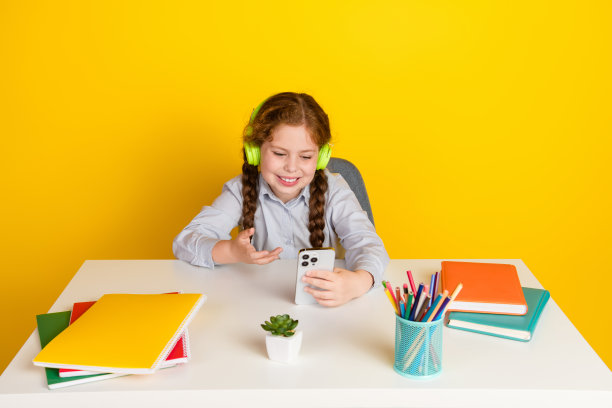小女生的照片讲视频通话智能手机穿着制服孤立的黄色背景图片下载