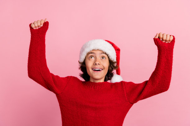 照片兴奋的孩子男孩举起拳头，抬头看空空间孤立的柔和的颜色背景图片下载