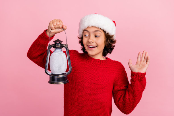 照片里的小男孩抱着圣诞灯看灯光孤立的粉彩背景图片下载