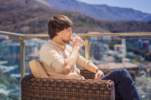 一个年轻人站在山后的阳台上喝咖啡图片下载