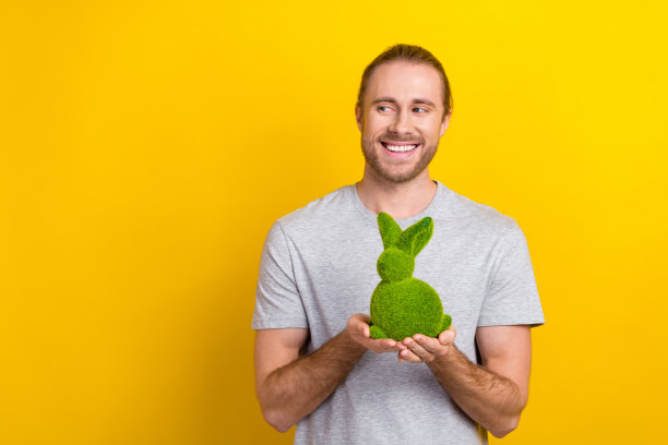 照片上，一个长着牙齿、笑容满面的男人，留着长发，穿着灰色t恤，在黄色的背景上看起来很空旷图片下载