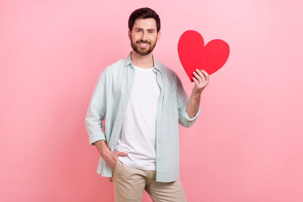 照片肖像迷人的年轻人愉快地拿着红色的大明信片礼物，穿着时髦的蓝色衣服孤立在粉红色的背景图片下载