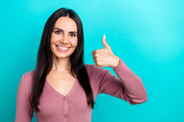 肖像照片开朗的年轻黑发女士牙齿灿烂的微笑大拇指新的广告产品孤立的海蓝宝石色背景图片下载