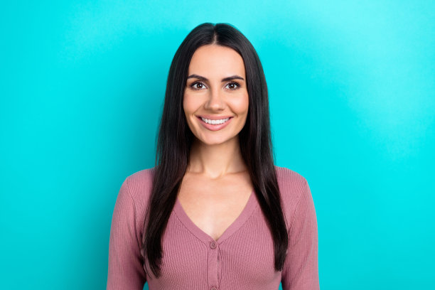 年轻迷人的漂亮女人的照片肖像，黑发，微笑，穿着衬衫，享受她完美的牙齿孤立的青色背景图片下载