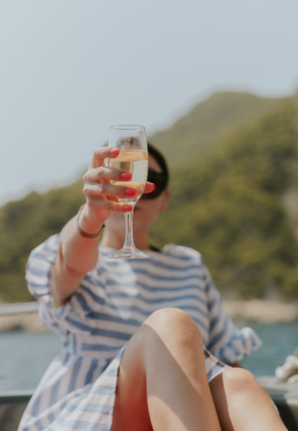 一个年轻女孩在船上喝香槟的画像。图片下载