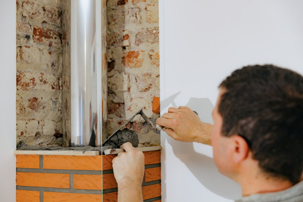 一个年轻人在壁炉的烟囱上砌砖。图片下载