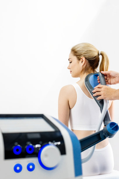 理疗师使用先进设备进行电磁疗法治疗背痛，展示有效的疼痛管理和康复技术图片下载