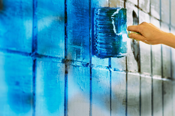 女艺术家的手用毛笔在墙上作画图片下载