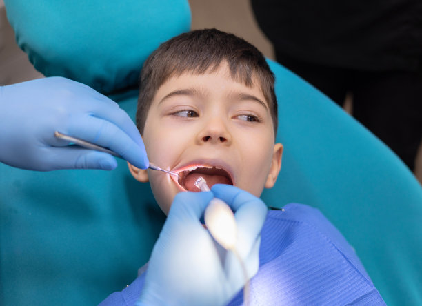 孩子在牙科诊所。牙科医生使用口镜和标量检查儿童牙齿。哭着流泪，伤心的男孩害怕。医生看着屏幕，补牙治疗。坐在椅子上的孩子正在接受检查图片下载