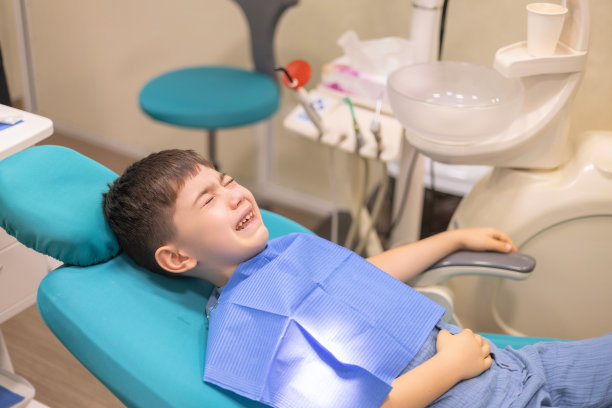 孩子在牙科诊所。牙科医生使用口镜和标量检查儿童牙齿。哭着流泪，伤心的男孩害怕。医生看着屏幕，补牙治疗。坐在椅子上的孩子正在接受检查图片下载